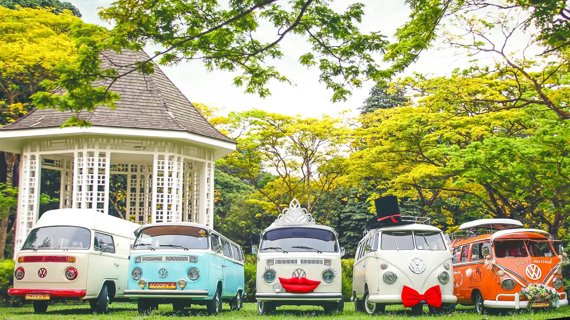 Five restored vintage Volkswagen Kombi vans from the Super Ice Cream Truck heritage fleet lined up in a Singapore garden, illustrating adaptive reuse of classic vehicles.